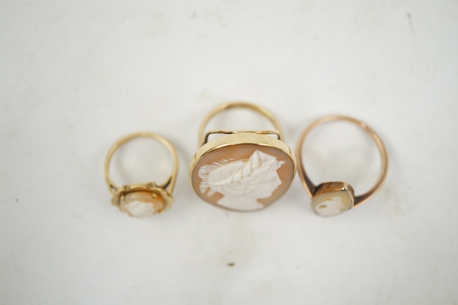 A group of three shell cameo rings, two depicting a classical lady in profile, one of navette-shaped outline depicting a dancing figure, each mounted in gold, two stamped 9ct, largest size V, largest cameo 3 x 2.4cm, com